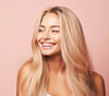 Blonde Frau mit langen, glaenzenden und voluminösen Haaren, laechelnd und zufrieden nach der Anwendung des Cocoair 2-in-1 Hairstylers, der föhnt und glättet gleichzeitig, für gesundes, geschmeidiges Haar ohne Hitzeschäden.